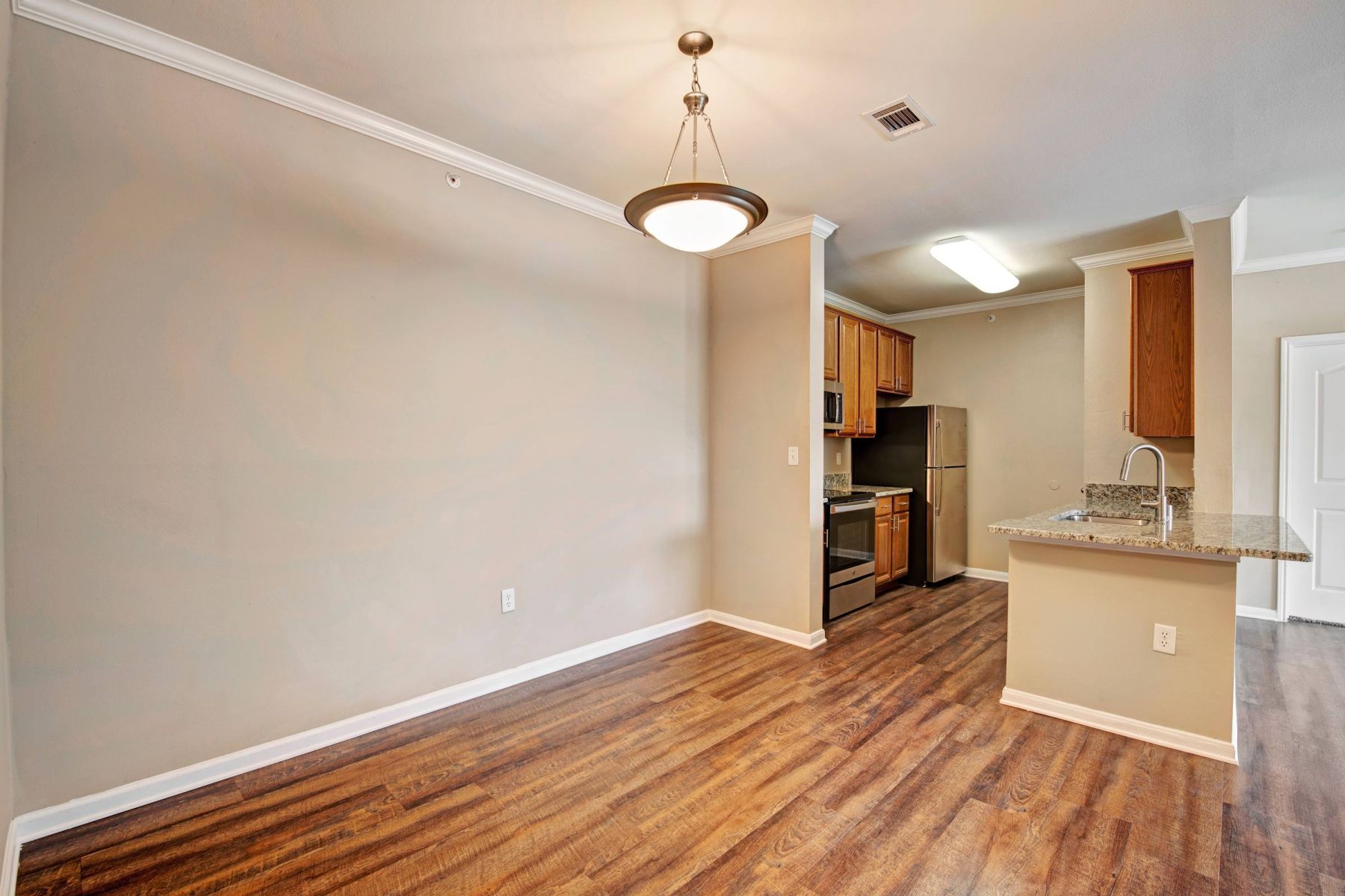 Empty room with wood floors, ceiling fan, and sliding glass door leading to a patio with vertical blinds at Apex West Midown.